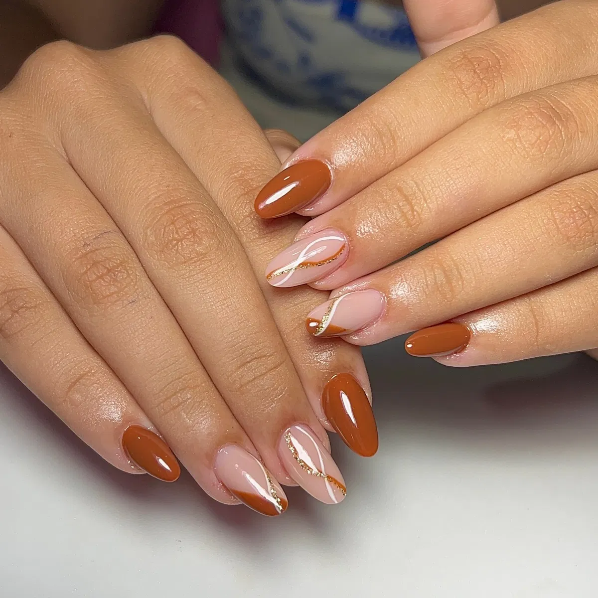 Brown and nude nails with diagonal gold-glitter striping