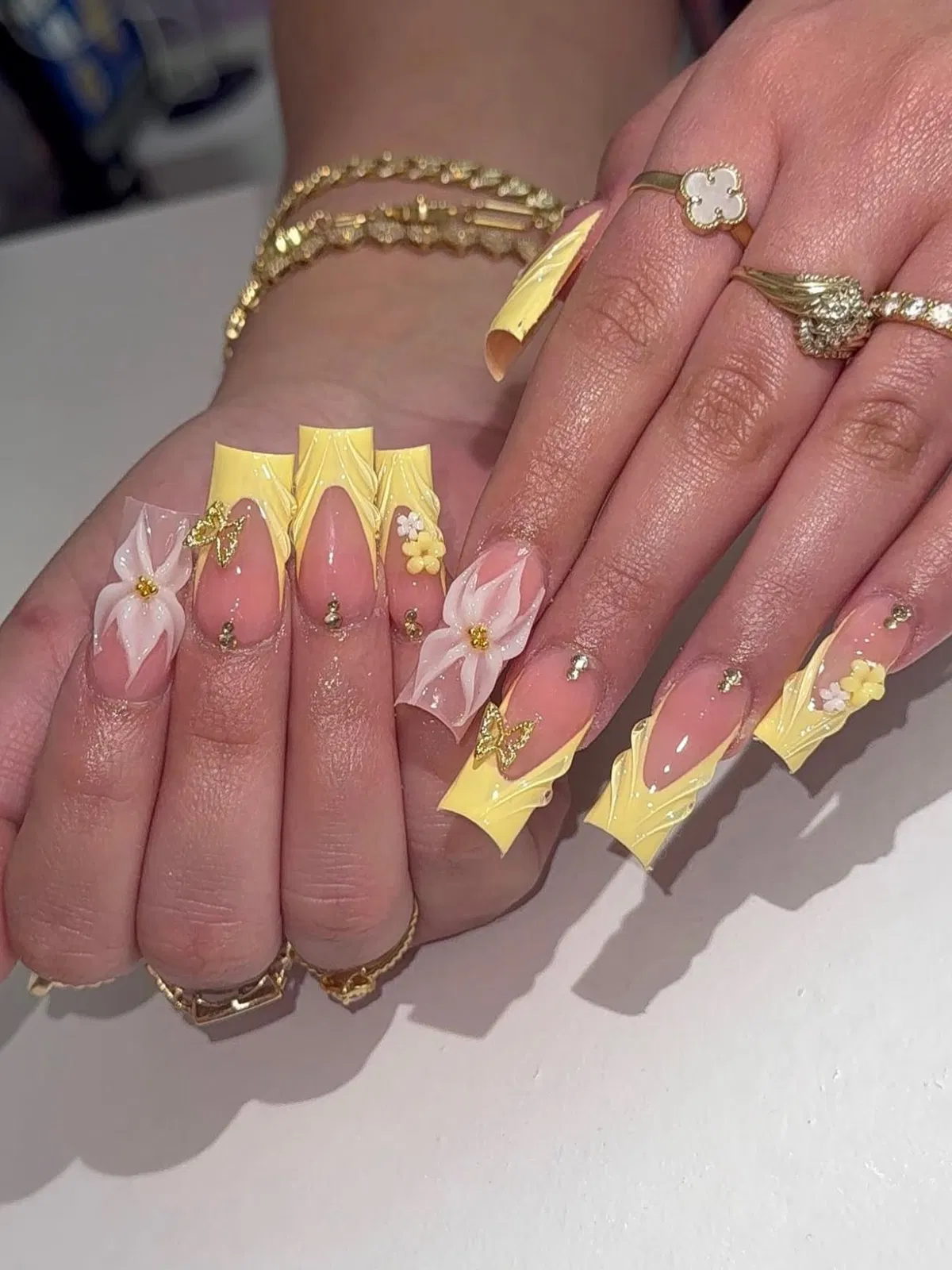 Long sculpted pale-yellow tips with white flowers and gold accents