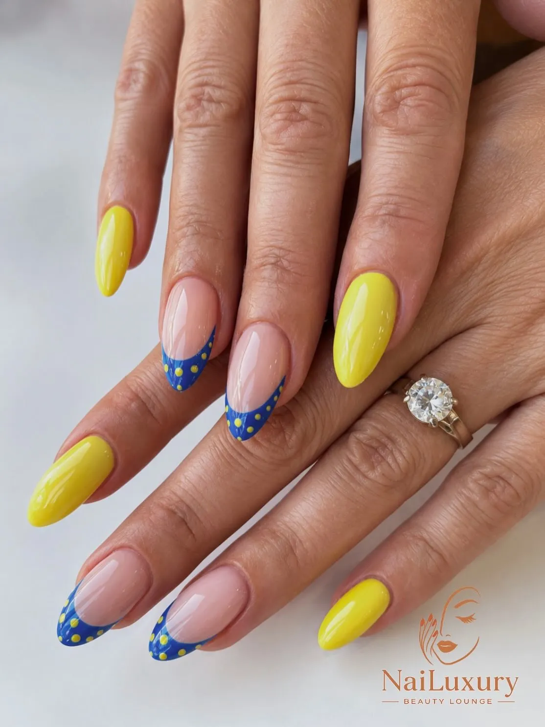 Pale yellow almond nails with rhinestone clusters and cross accents
