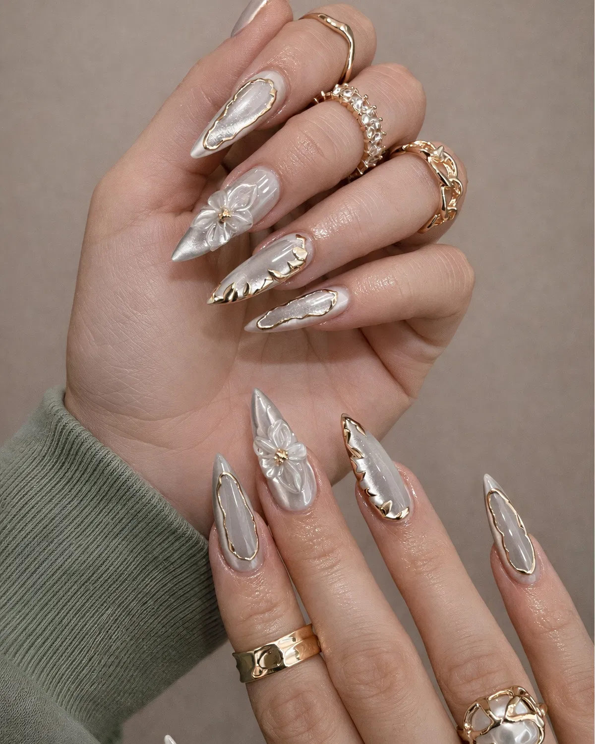 Pearly stiletto nails with irregular gold frames and 3D flowers