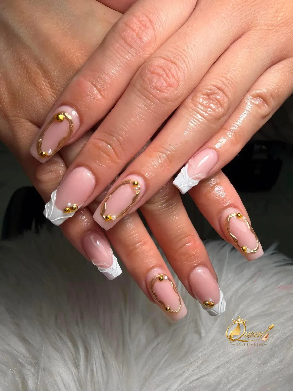 Square nude-pink nails with raised white tips and gold outlining