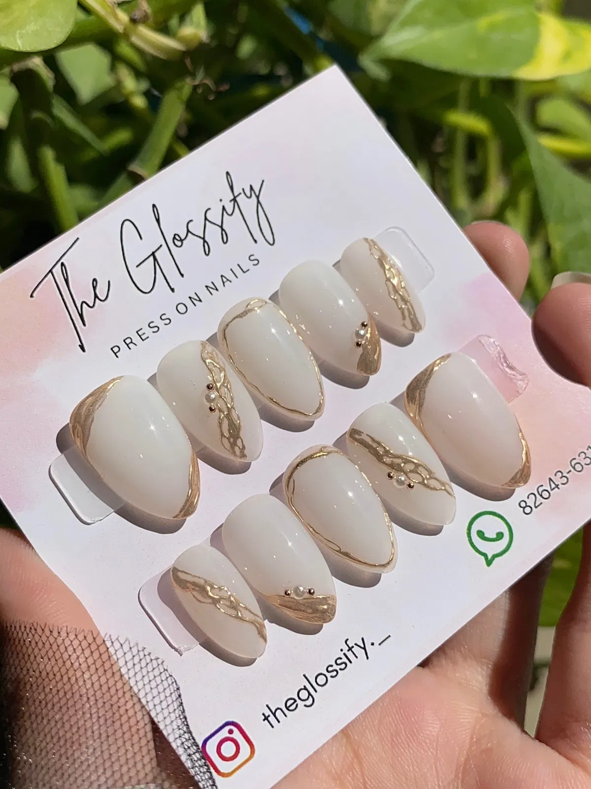 Glossy white press-ons with gold striping and pearl accents