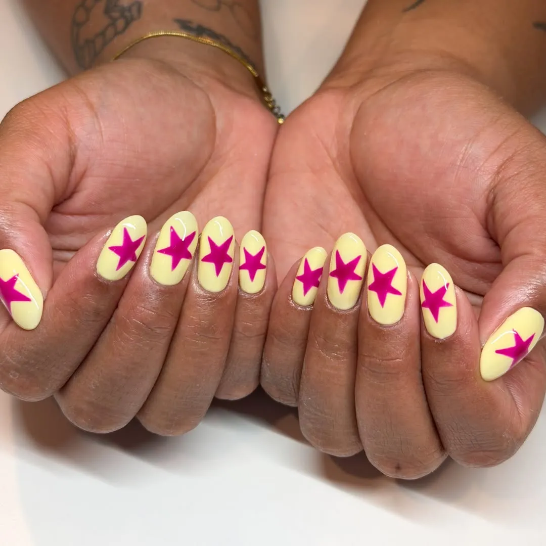 Pale yellow nails with bold hot-pink stars