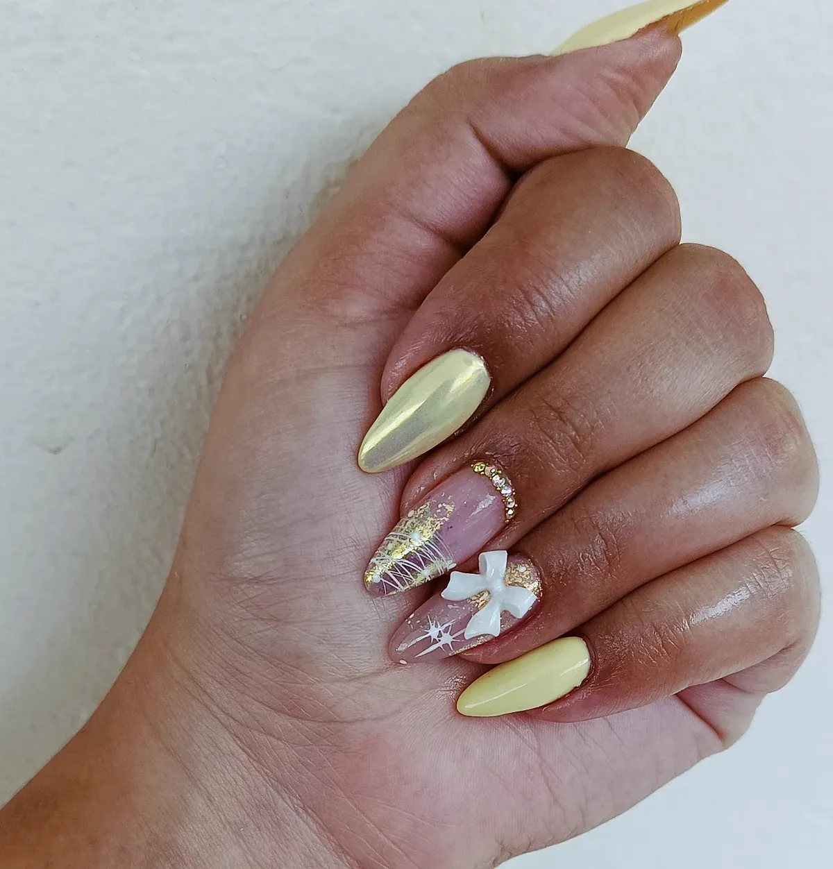 Pale yellow pearly nails with bow accent