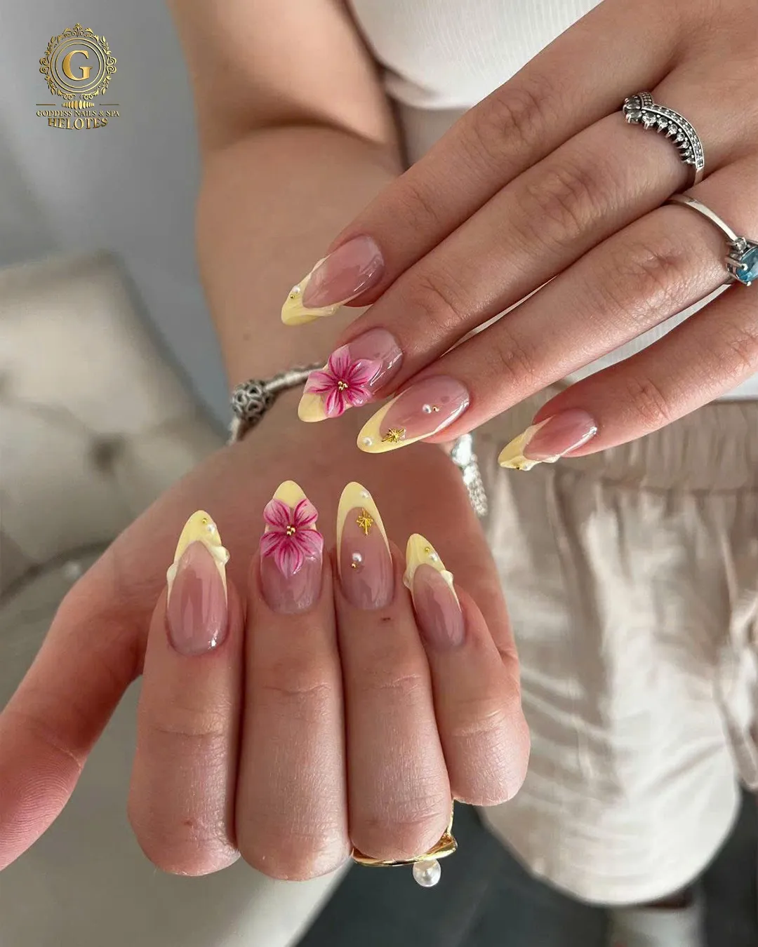 Soft yellow French tips with pink floral and small gold accents