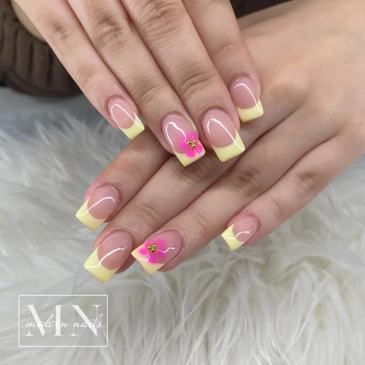 Pale yellow French tips with hot pink floral pop accents