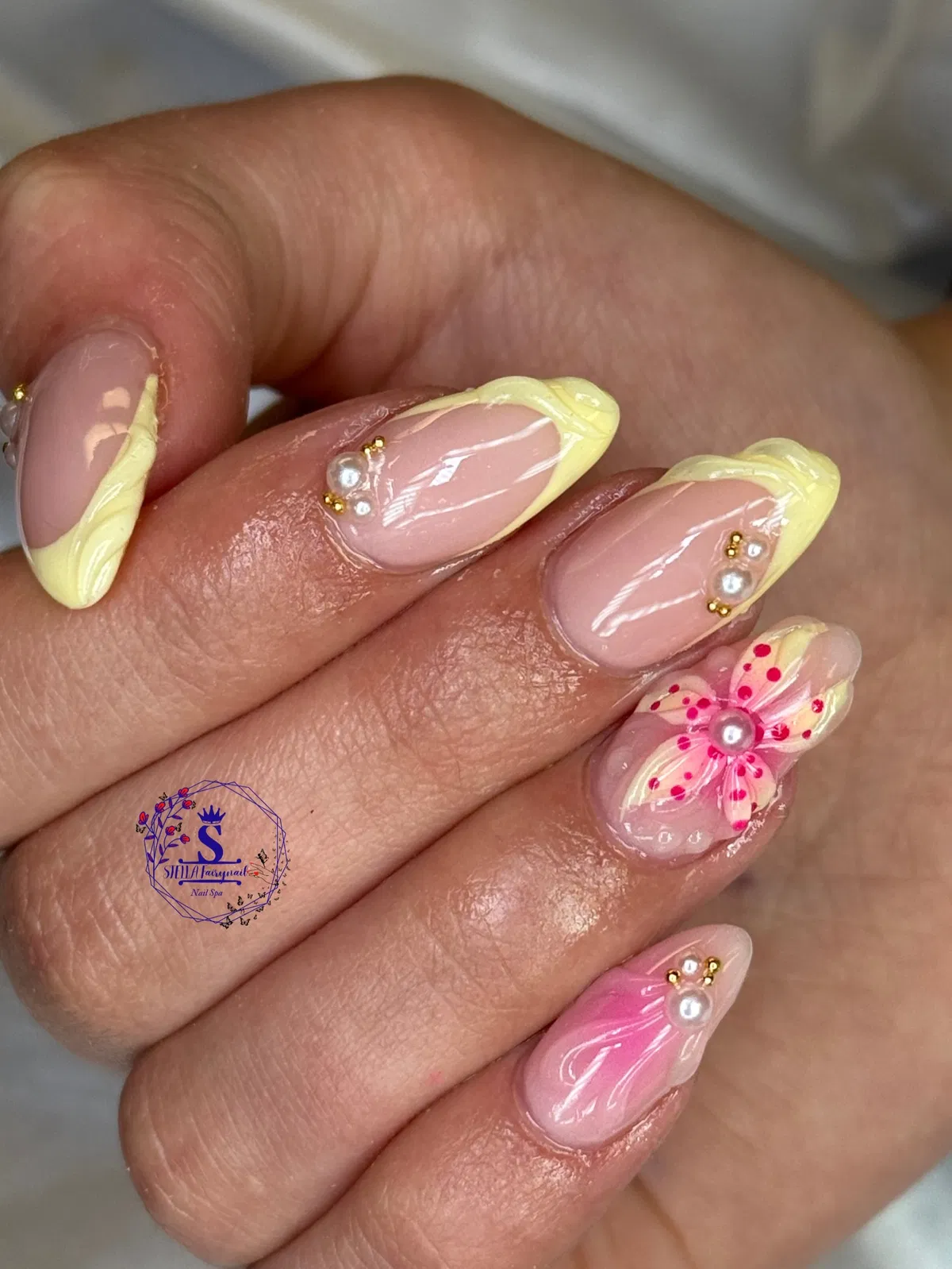 Swirled pale-yellow French tips with pearls and a 3D flower accent