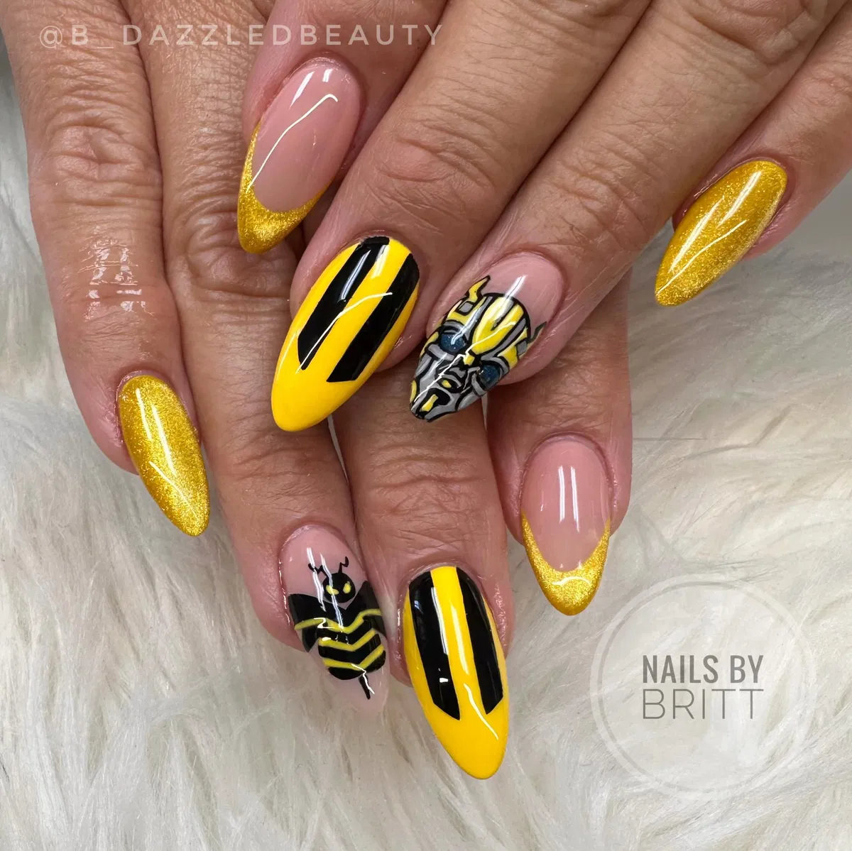 Gold glitter French tips with bold black stripes and graphic character art