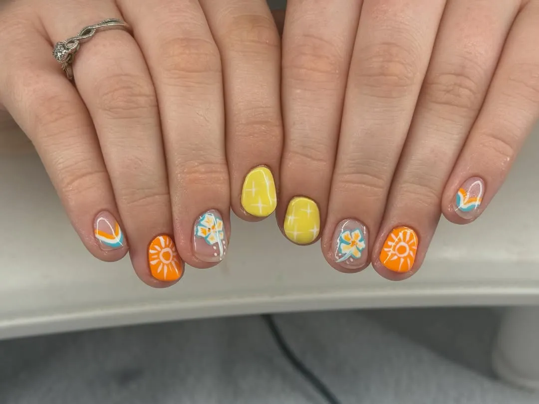 Playful yellow-and-orange nail art with suns and grids