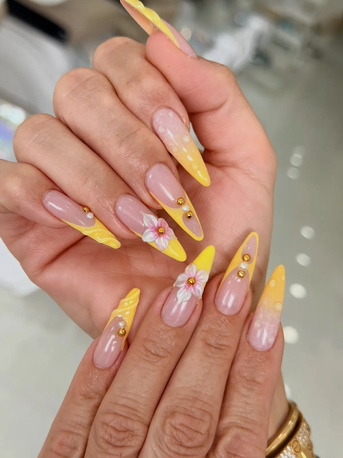 Pointed yellow French tips with floral and stud accents