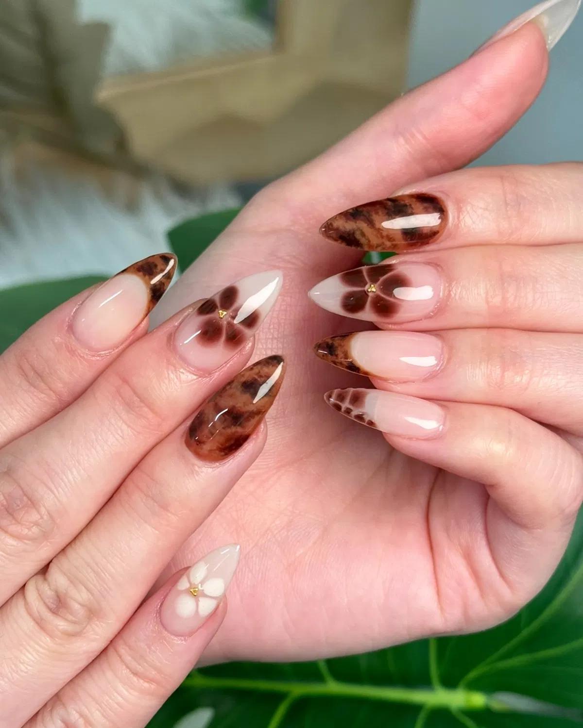 Glossy nude set with brown tortoiseshell-style tips and floral studs