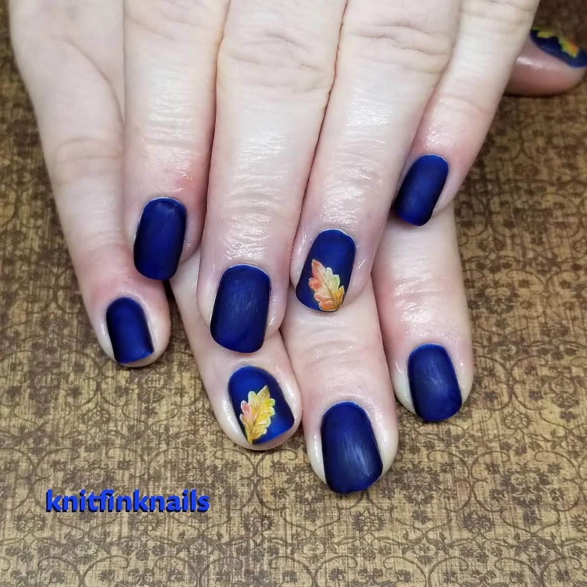 Matte navy nails with small gradient leaf accents