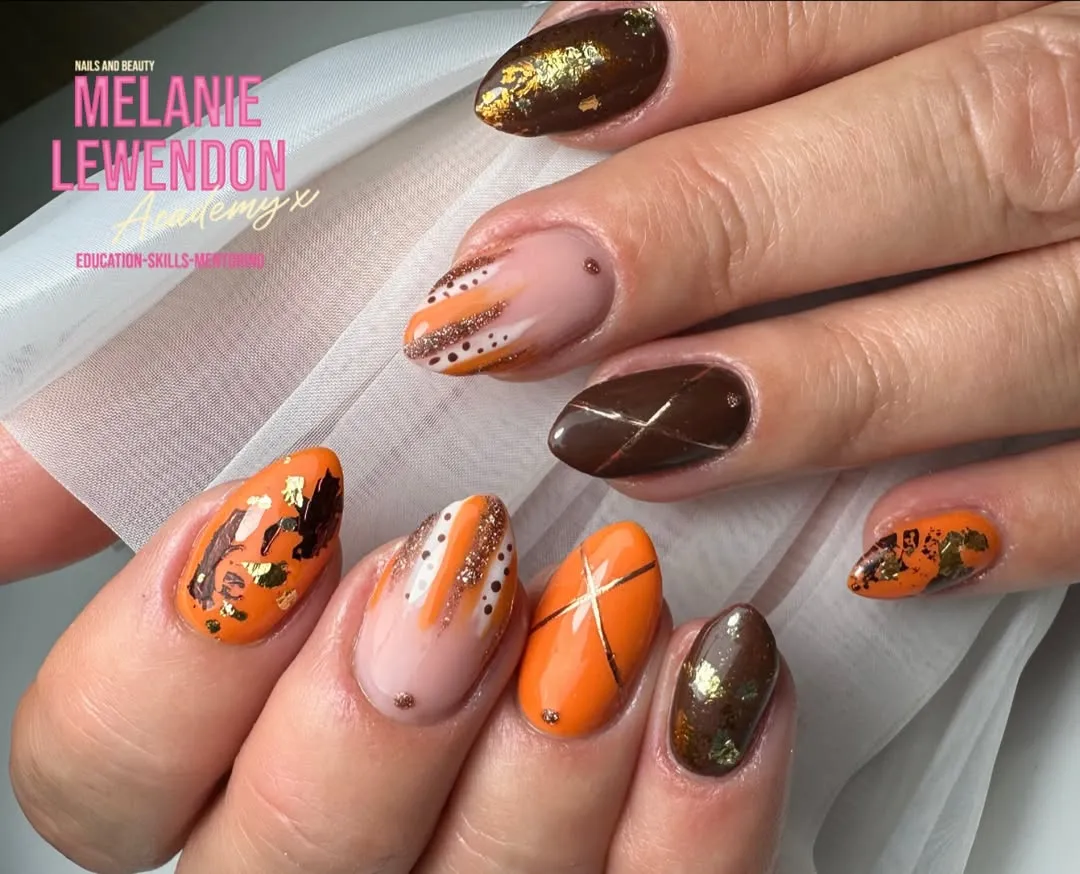 Orange, nude, and brown nails with linework, dots, and gold flecks