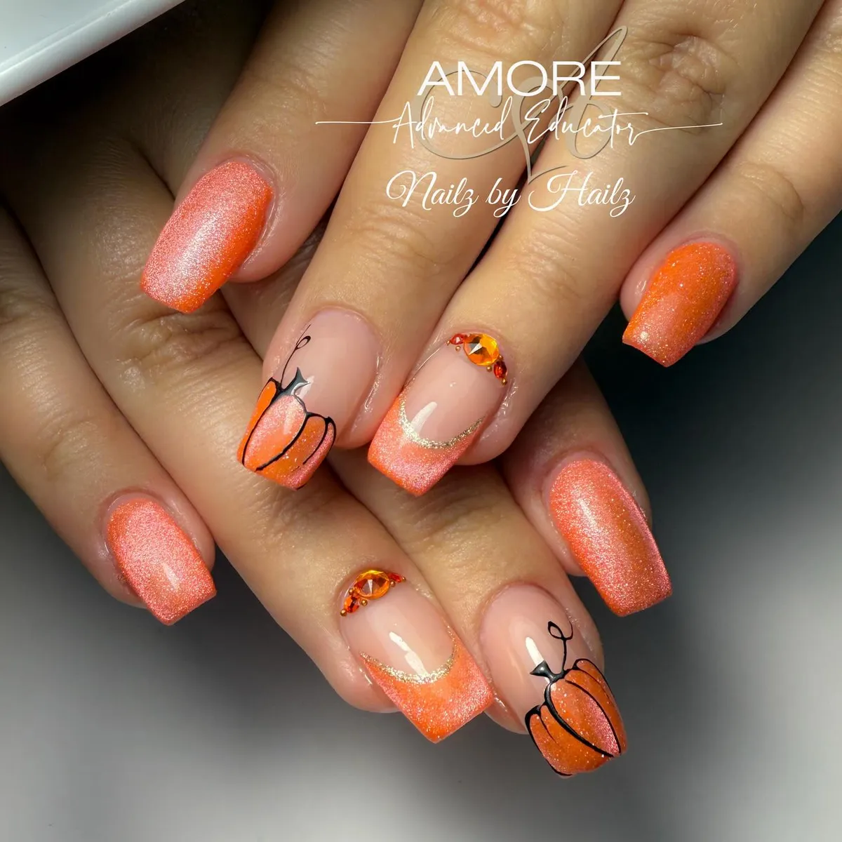 Shimmery orange set with nude gradient tips, pumpkin line art, and orange gems