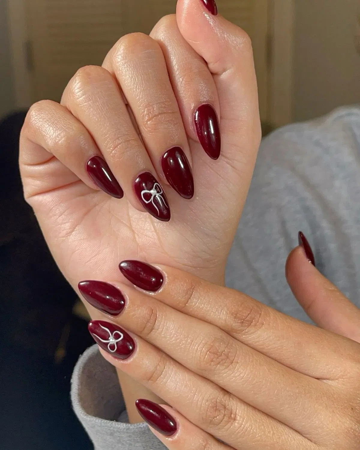 Glossy burgundy nails with white bow outlines
