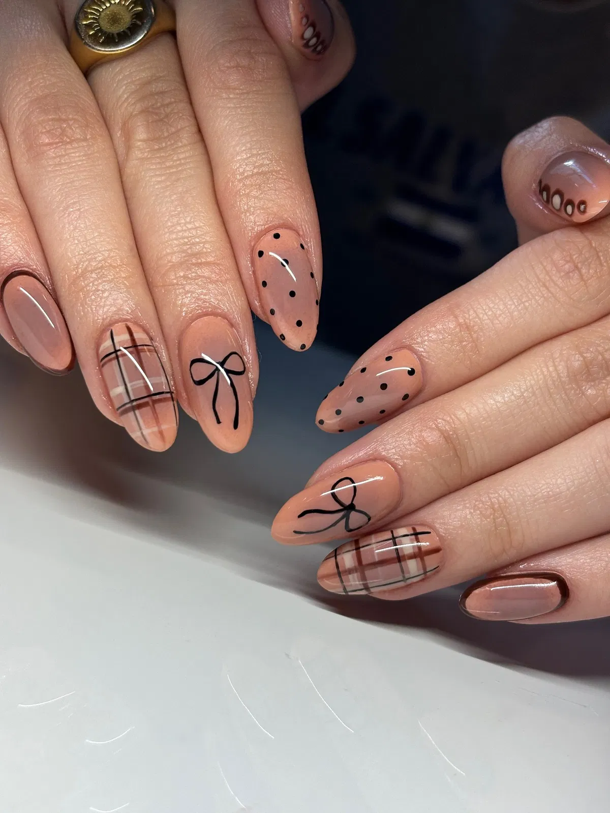 Nude almond nails with plaid, bows, and polka dots