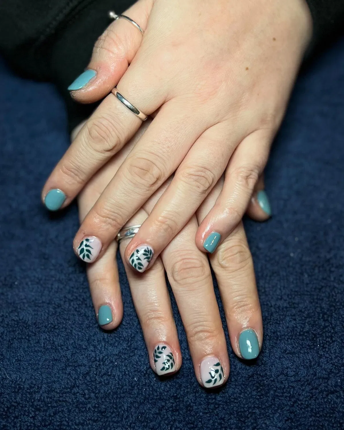 Muted teal-blue with leafy accent nails on a pale base