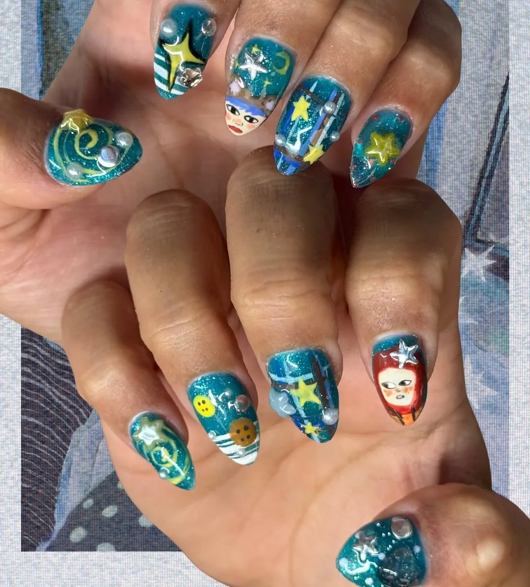 Teal glitter stiletto nails with 3D stars, domes, and illustrated faces
