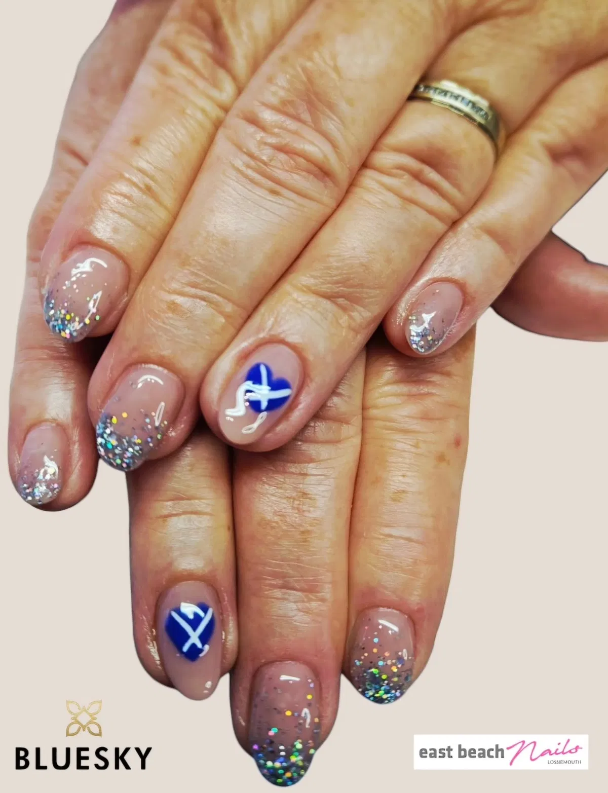 Nude glitter tips with blue heart-and-cross accents