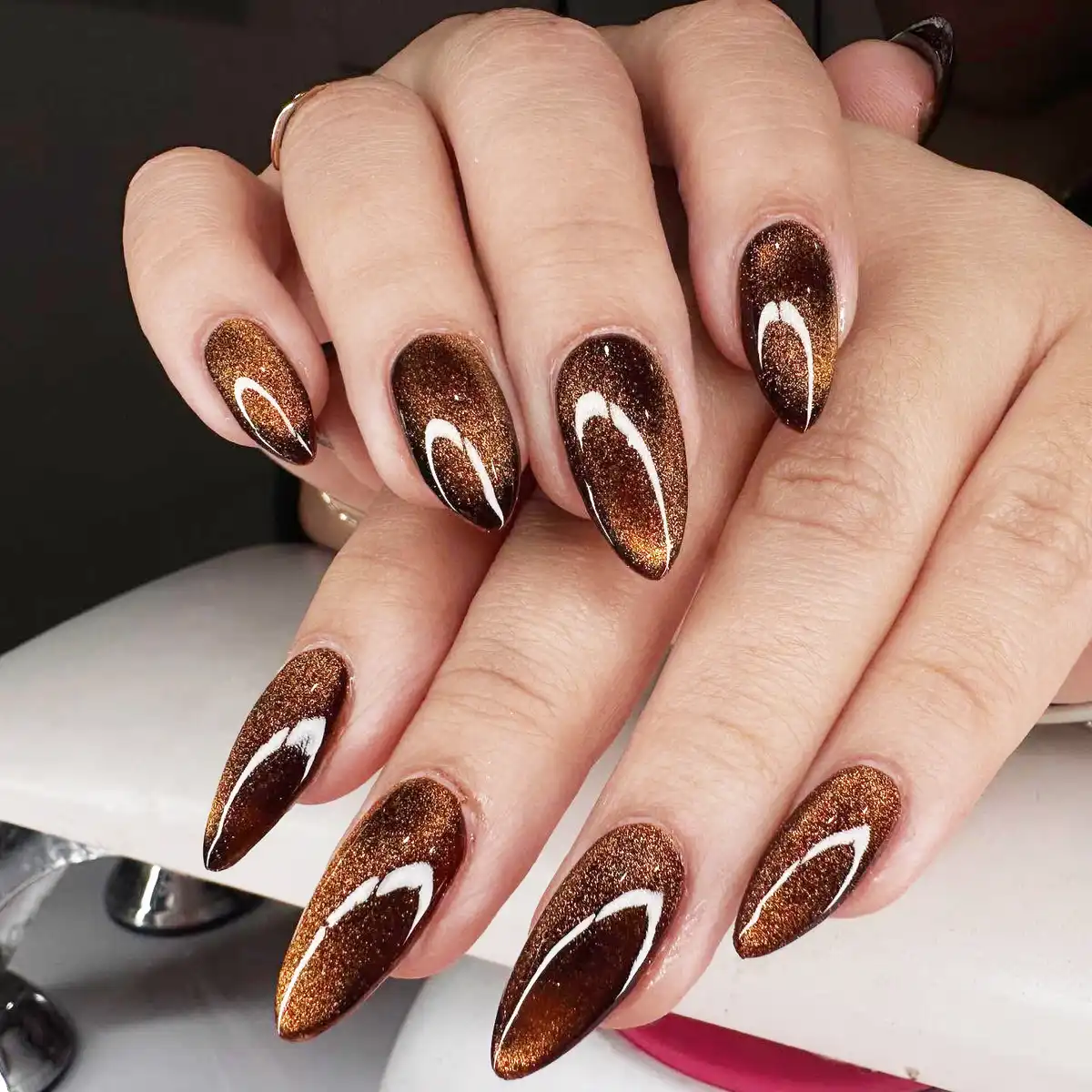 Long copper-brown glitter nails with curved highlights