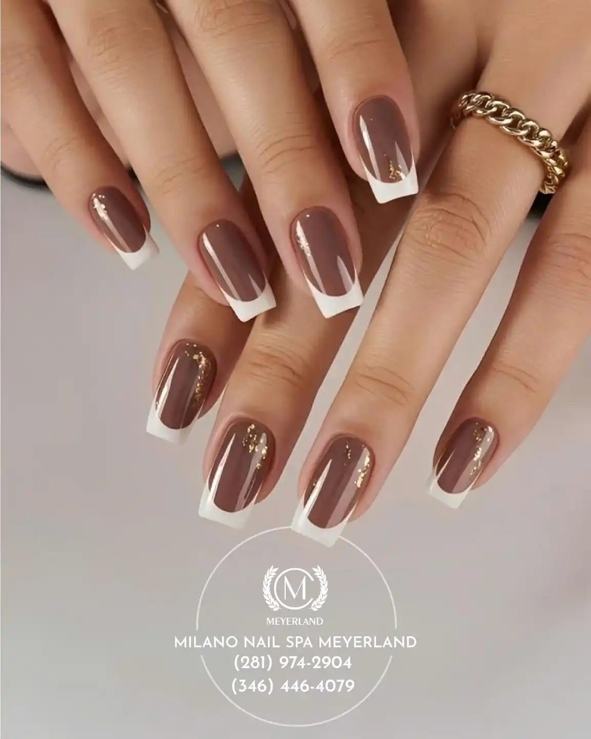 Glossy brown nails with crisp white tips and gold streaks