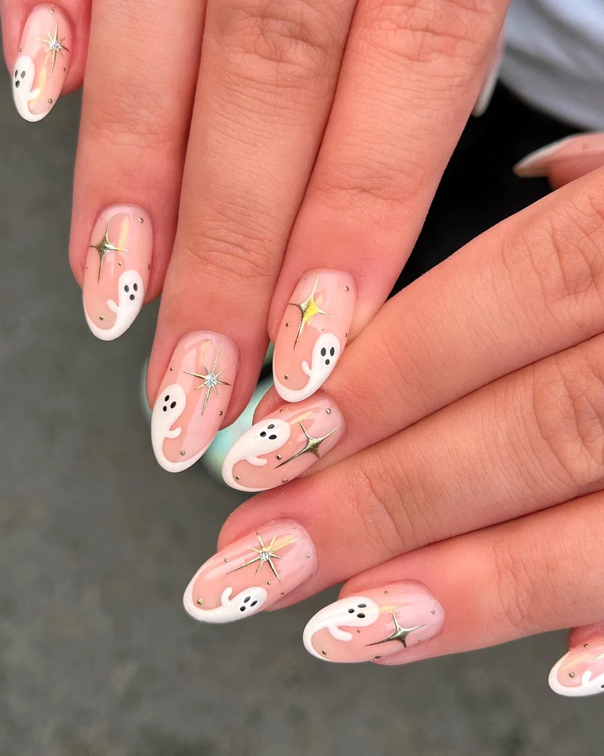 Nude-Pink Almond Nails with White Ghosts and Gold Starbursts