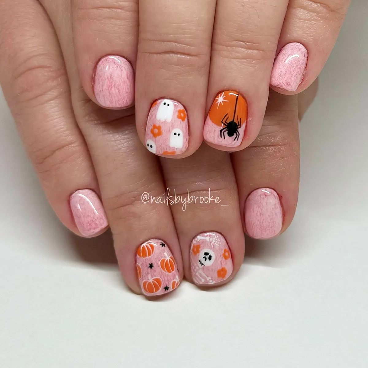Pink nails with tiny ghosts, pumpkins, and a spider accent