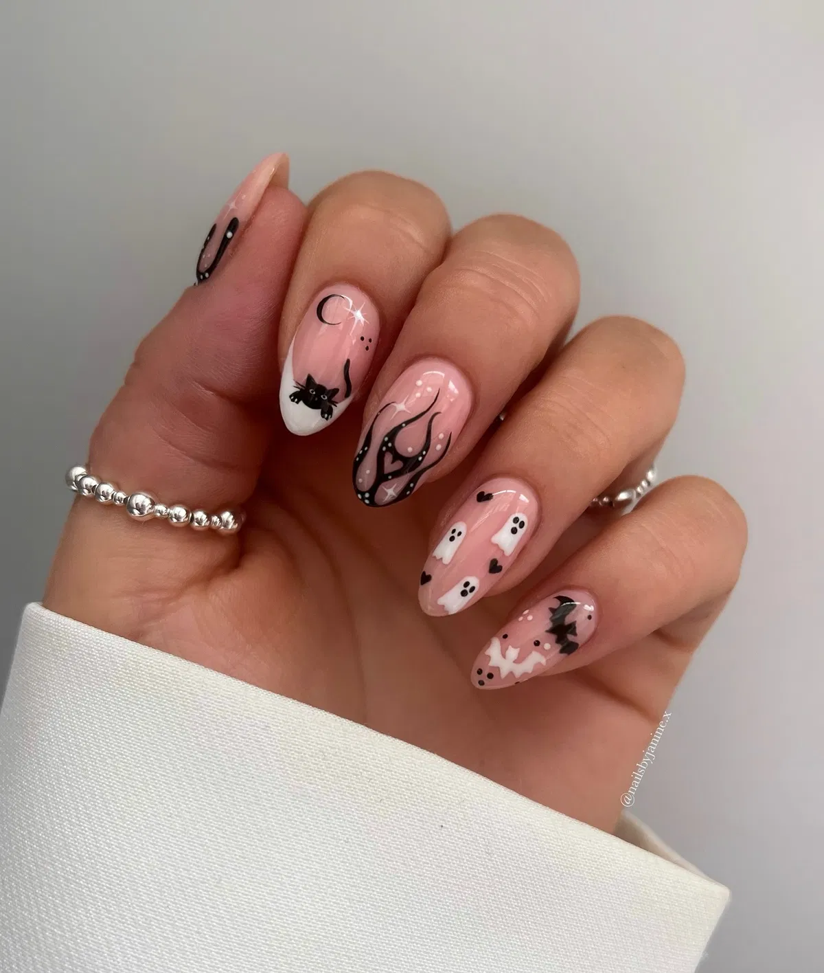 Sheer pink nails with black flames, tiny ghosts, and a bat accent