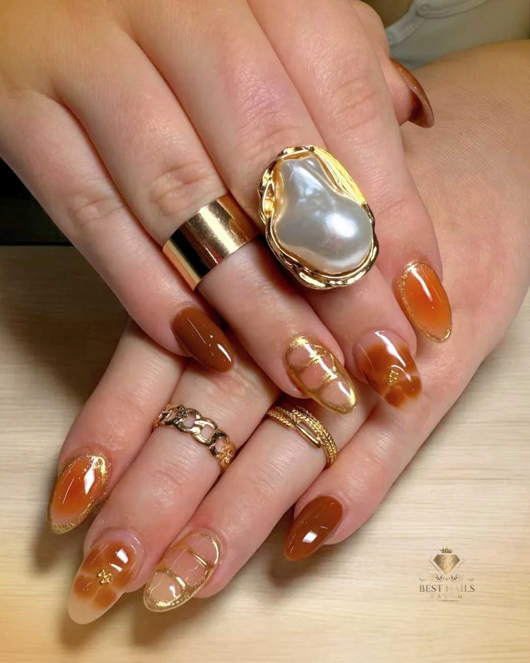 Caramel-brown nails with gold edging and nude-gold line accents