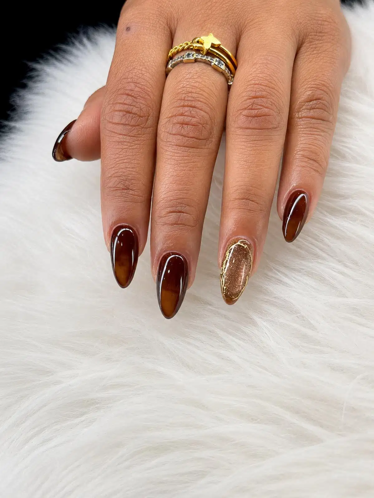 Deep brown translucent-effect nails with a gold glitter framed accent