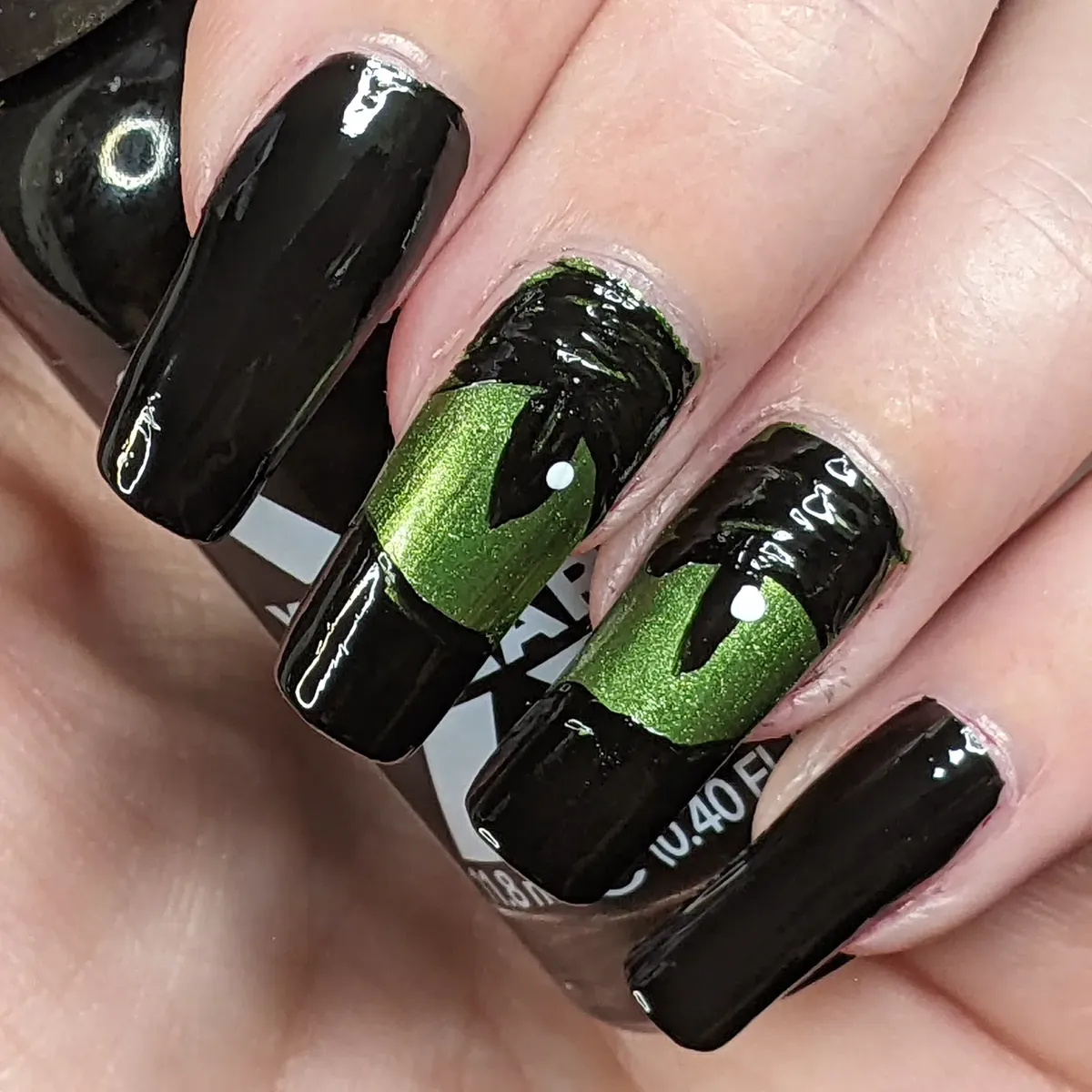 Black nails with metallic green panels and black silhouette detail