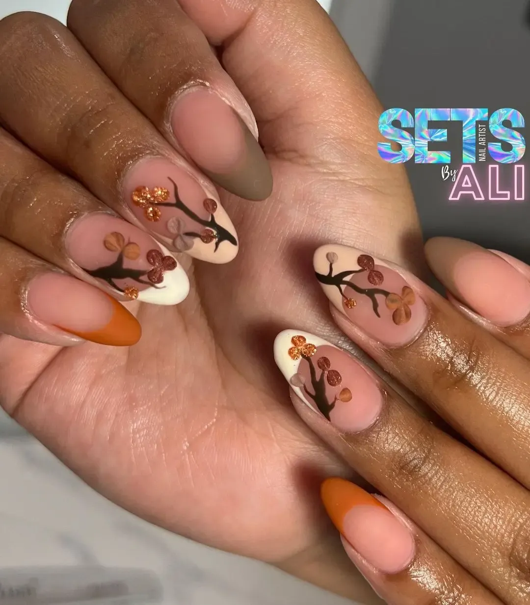 Nude-pink French tips with branch-and-flower nail art