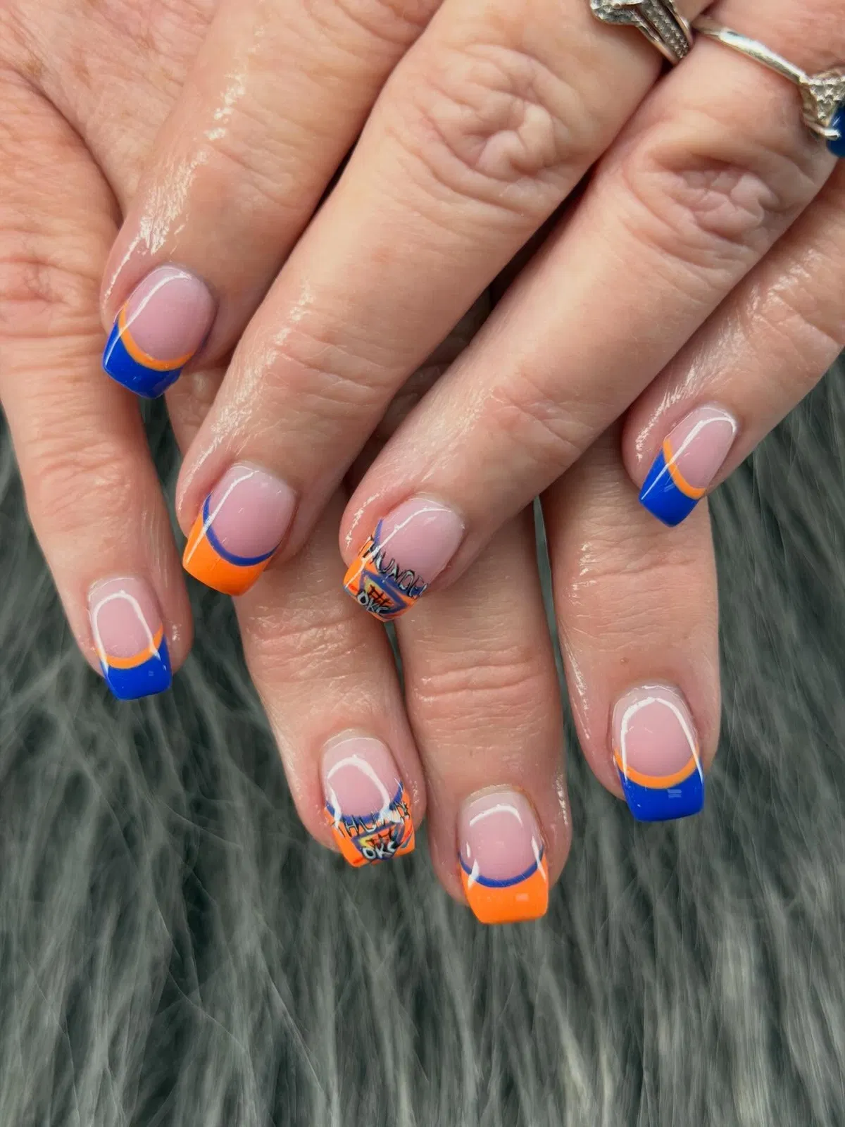 Orange-and-blue swoosh French tips with 'OKC' accents
