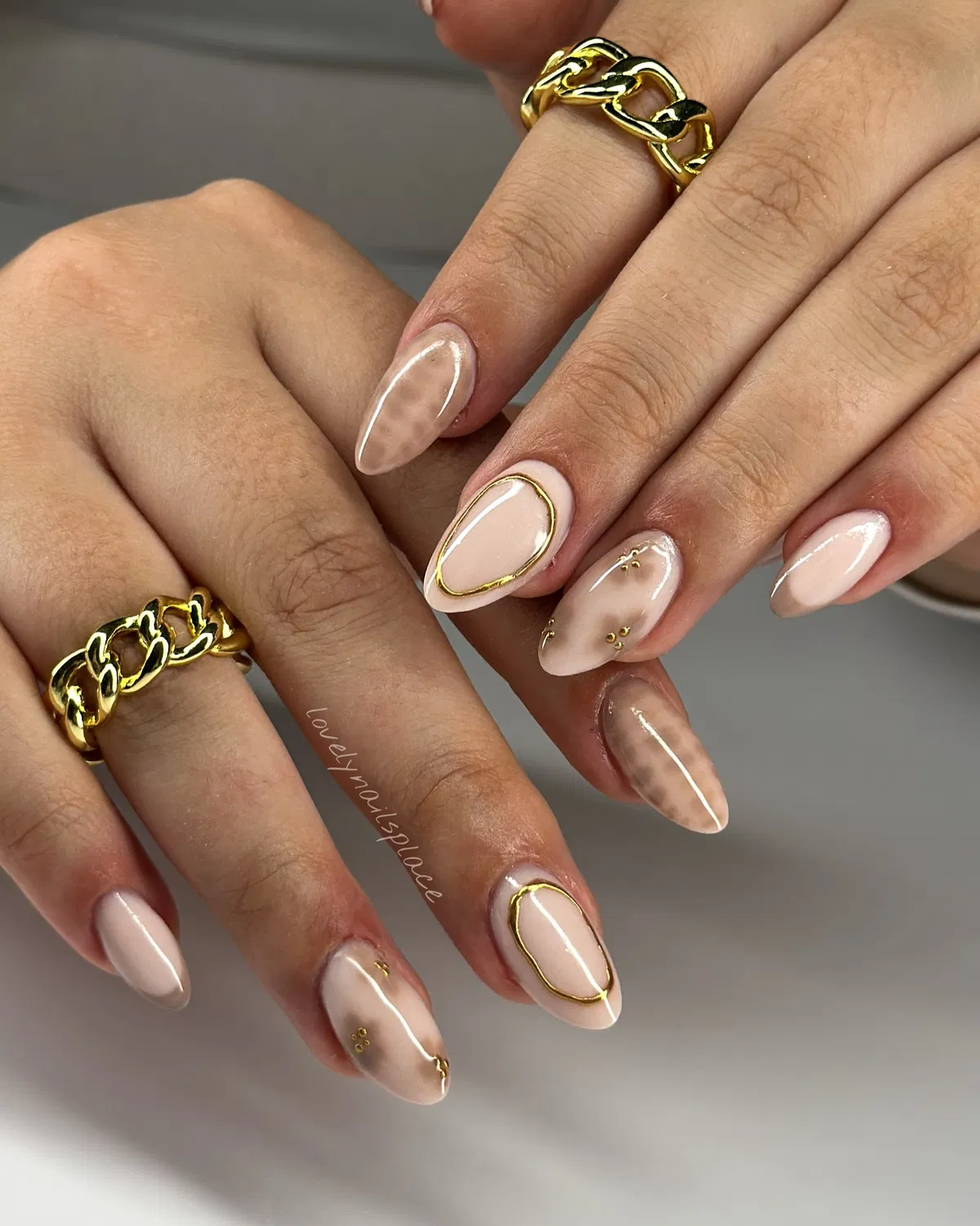 Neutral almond nails with gold outlines and subtle marbling