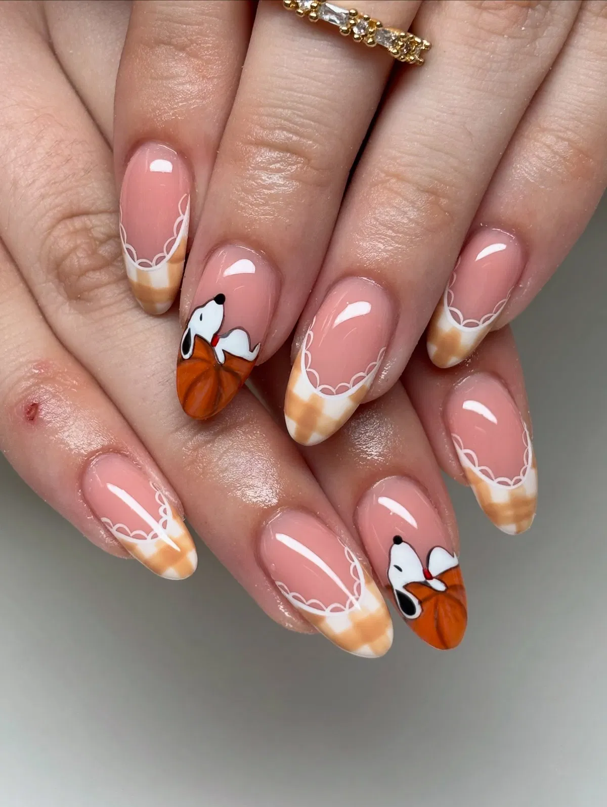 Pink nude nails with scalloped French details and cartoon dog-pumpkin art