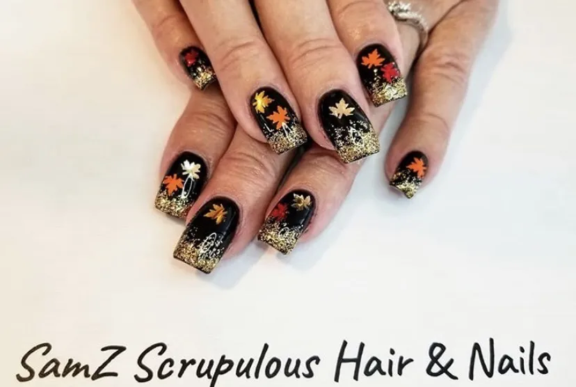 Black nails with gold glitter tips and leaf motifs
