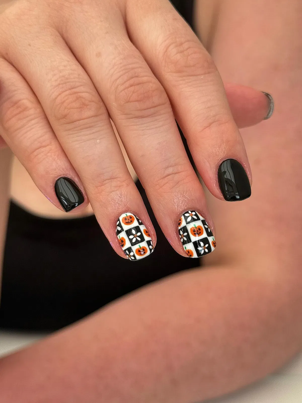 Black nails with checkered pumpkin-and-flower accents