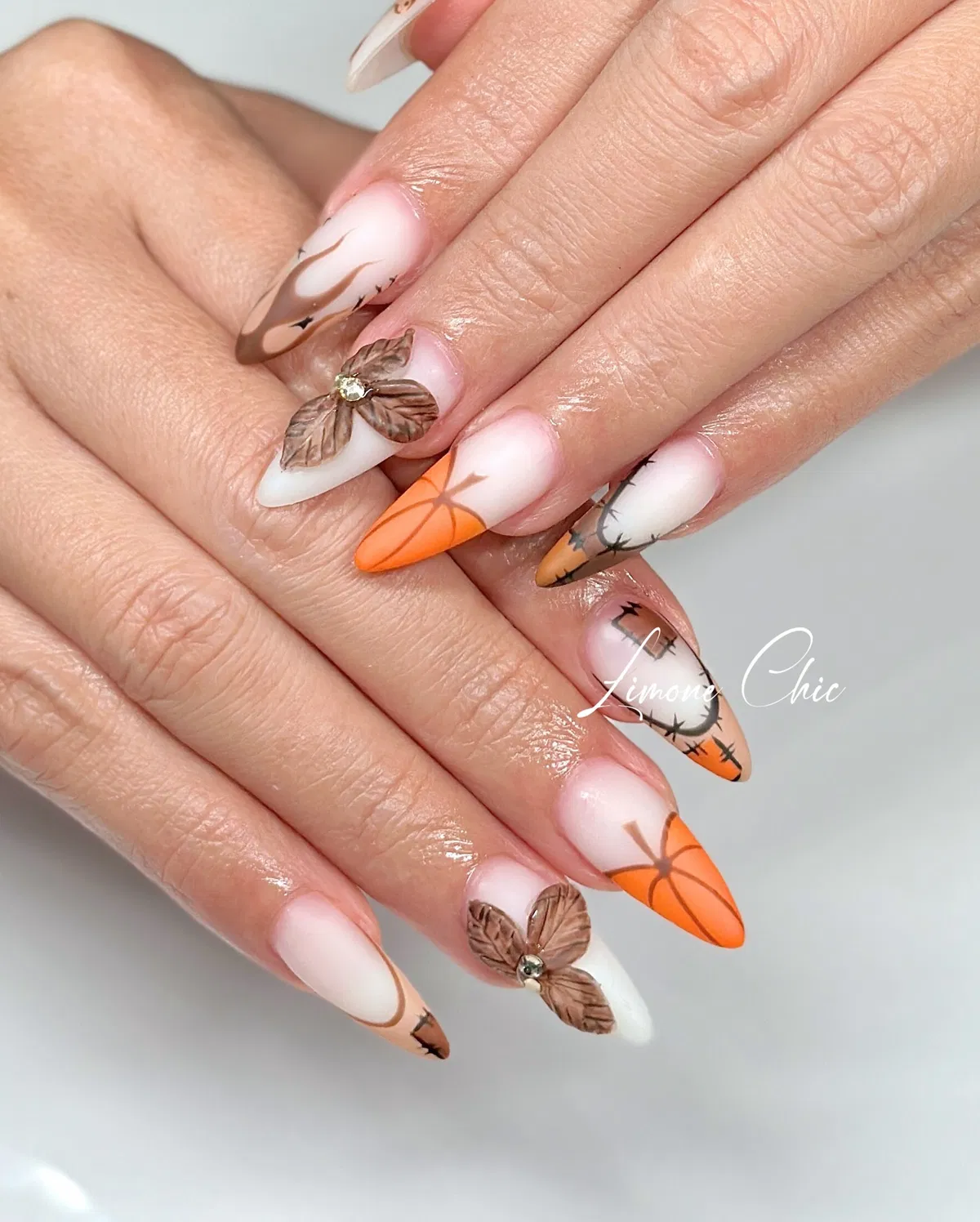 Stiletto ombrรฉ with orange tips, branch lines, and 3D floral accents