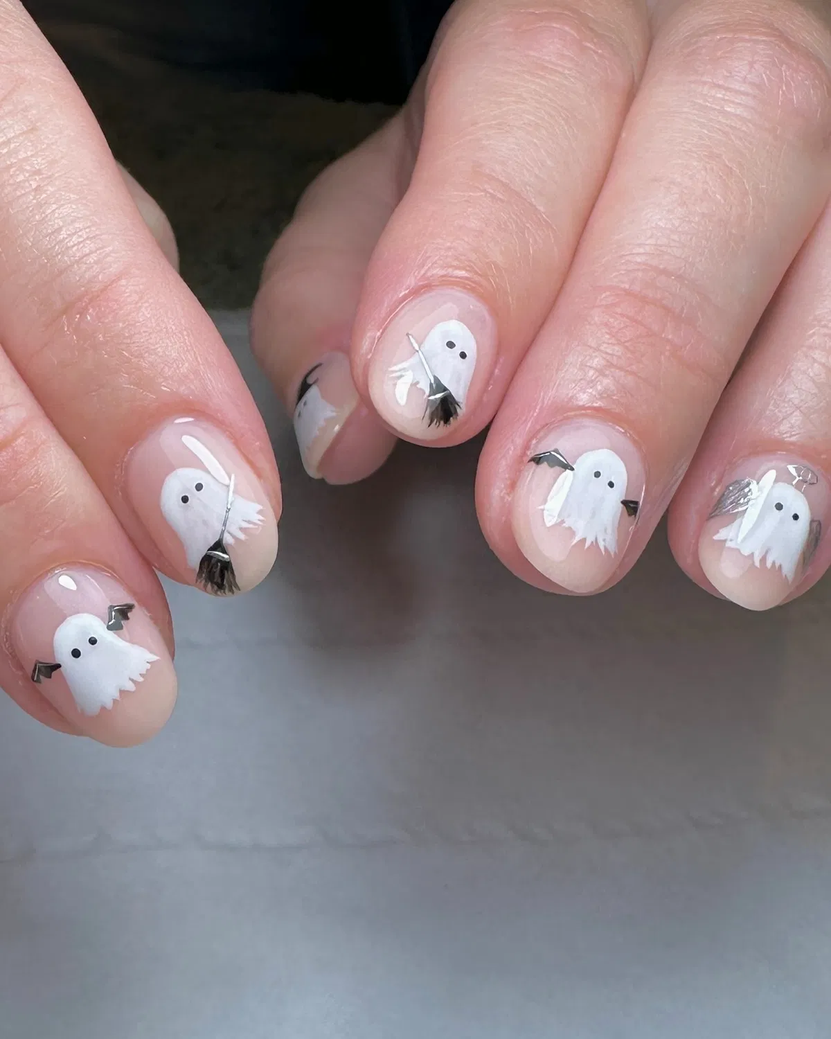 Sheer nude nails with tiny white ghosts and small black accents