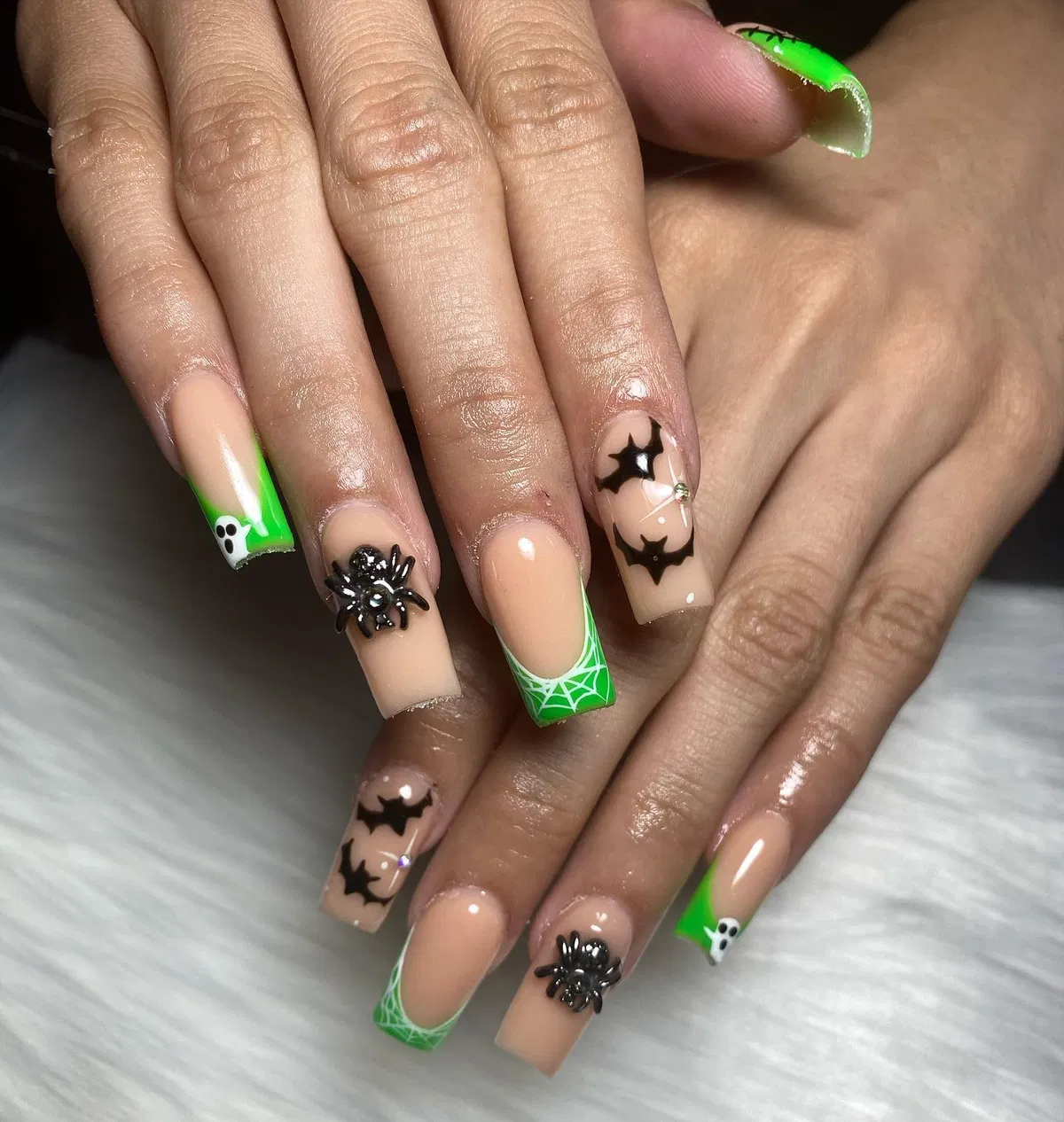 Nude nails with green web tips, bats, and raised spider accents