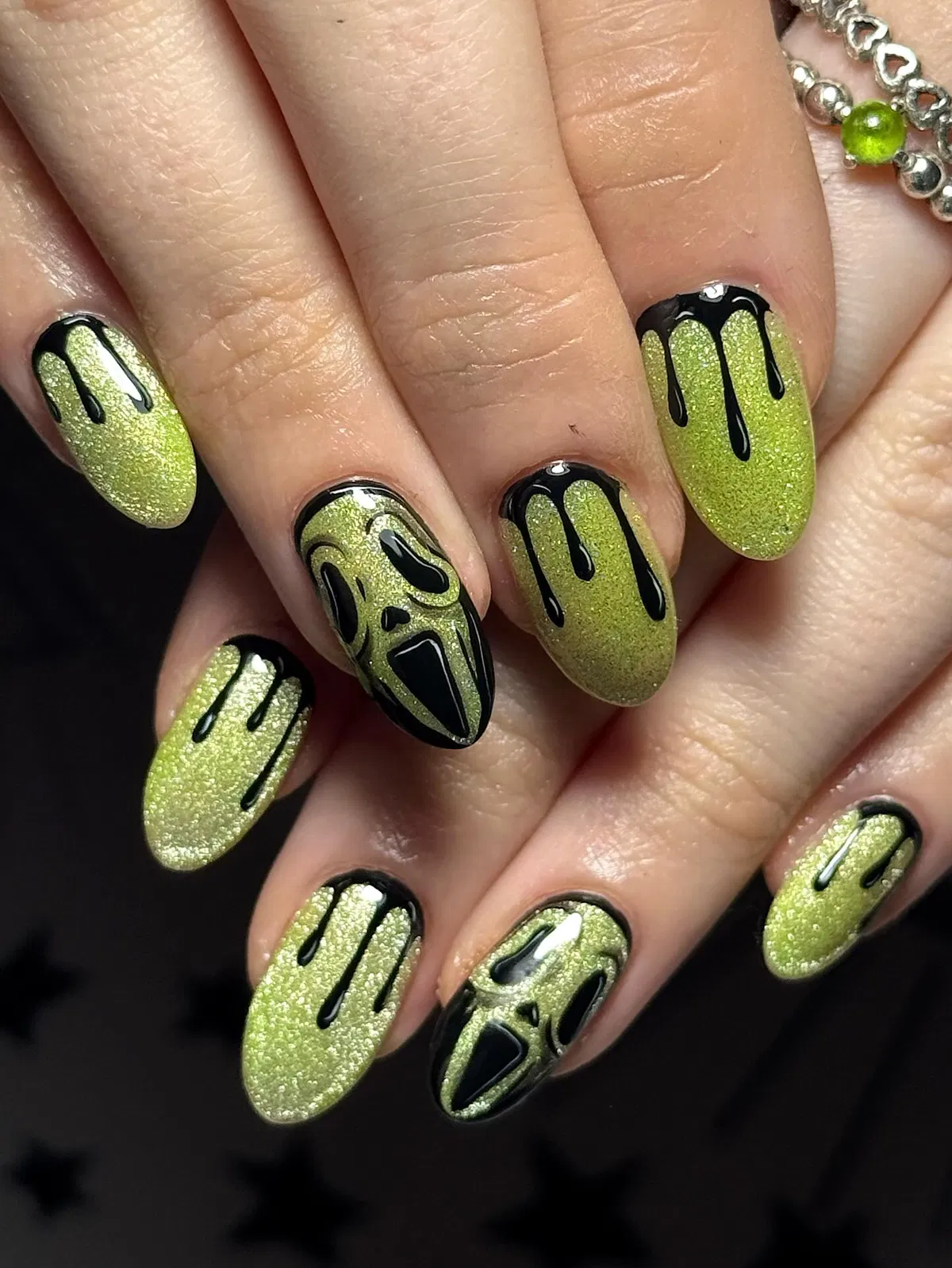 Green shimmer nails with black drips and mask-like face accents