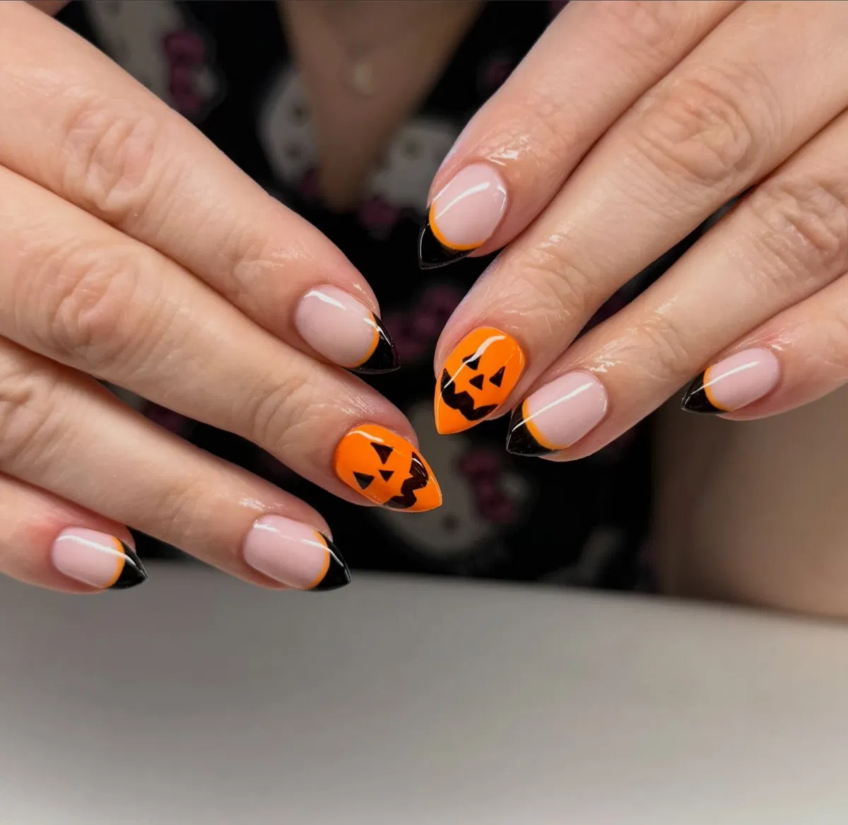 Nude-and-black French tips with orange jack-o'-lantern accents