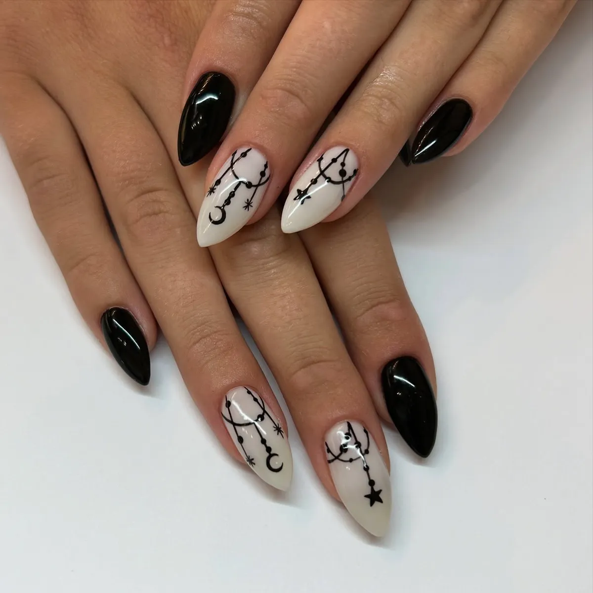 Stiletto black nails with white celestial line art