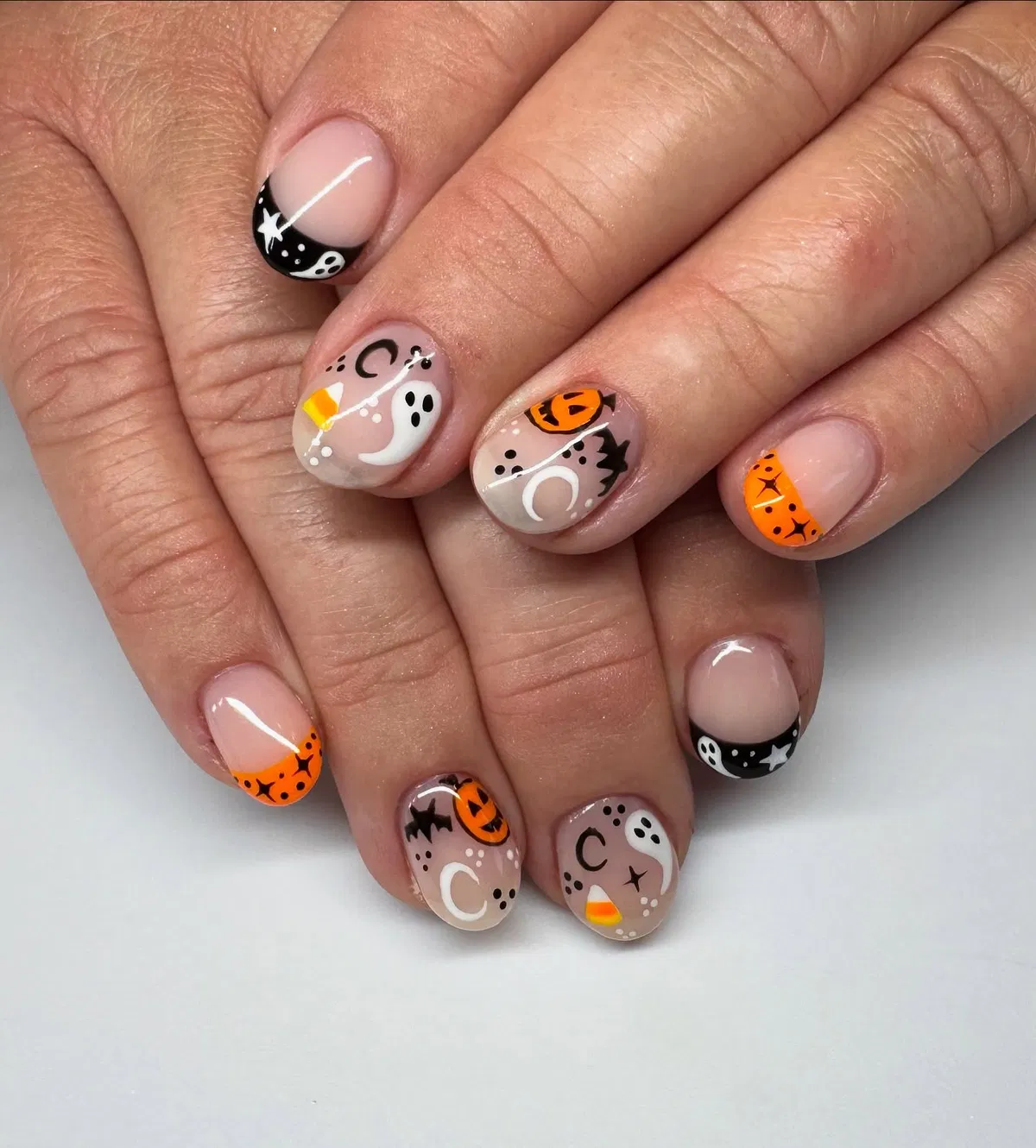 Nude base with orange/black French tips and mixed Halloween icons