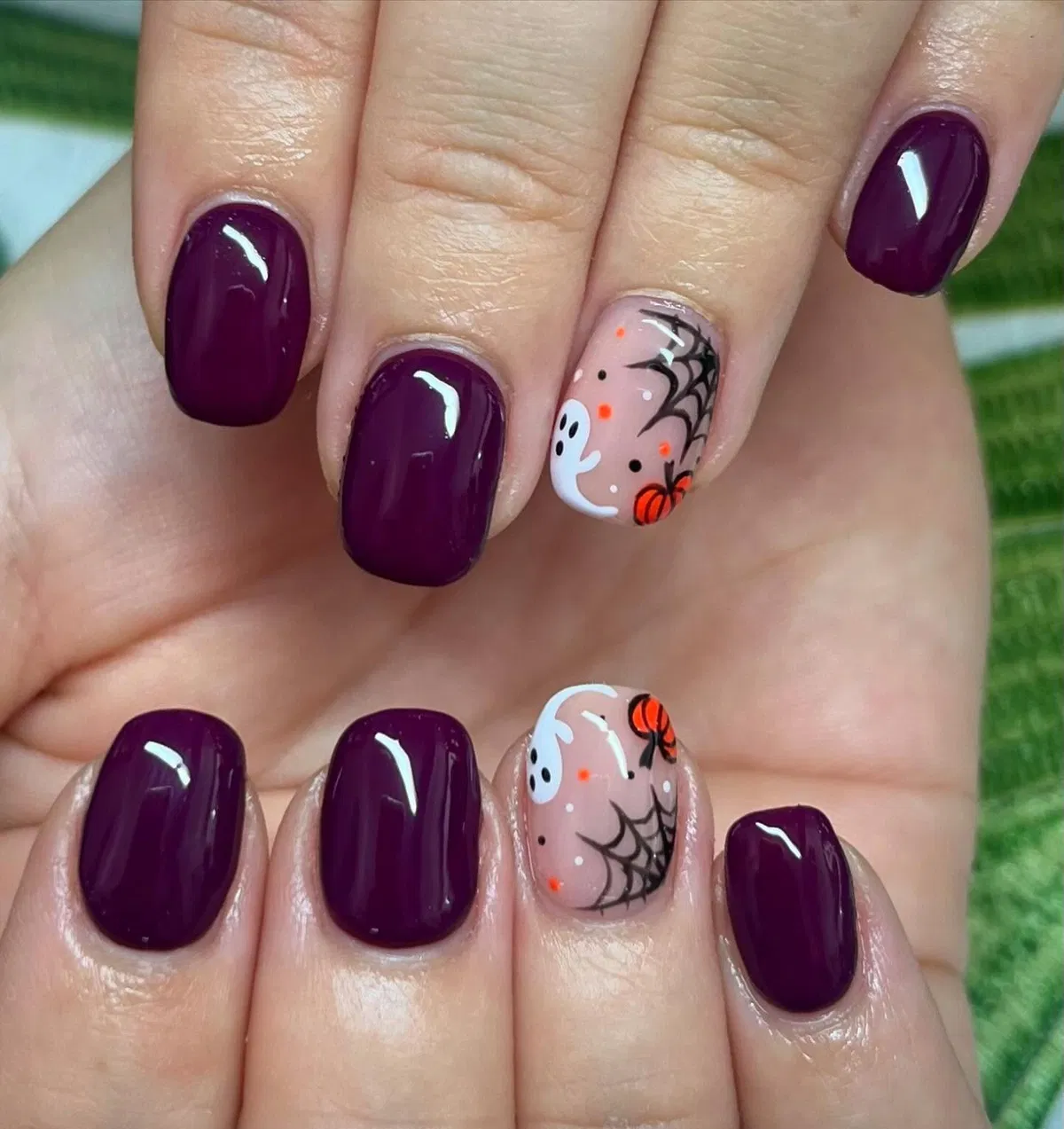 Deep purple nails with ghost-and-spiderweb accents