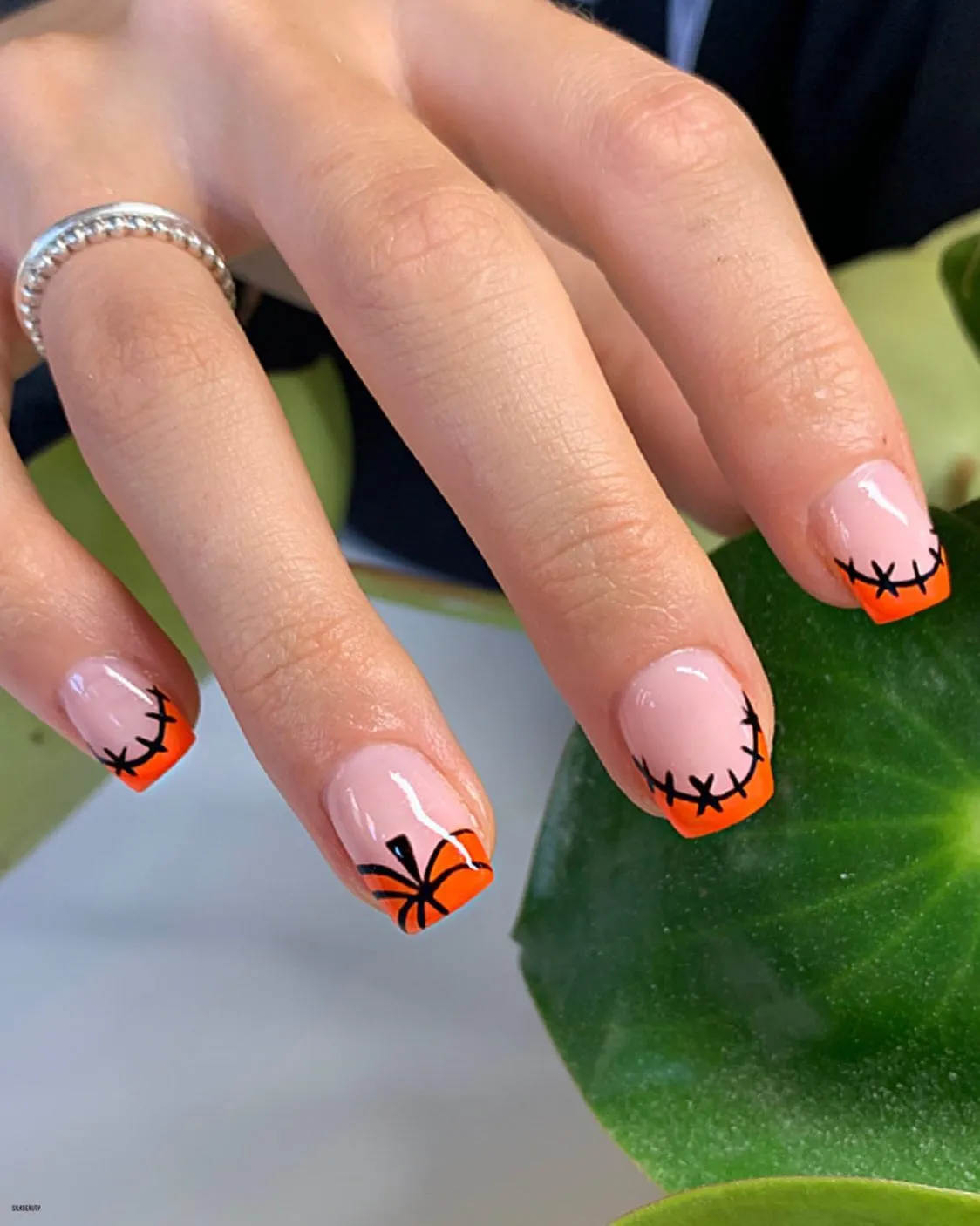 Pink base with orange French tips and black stitched/spider graphics