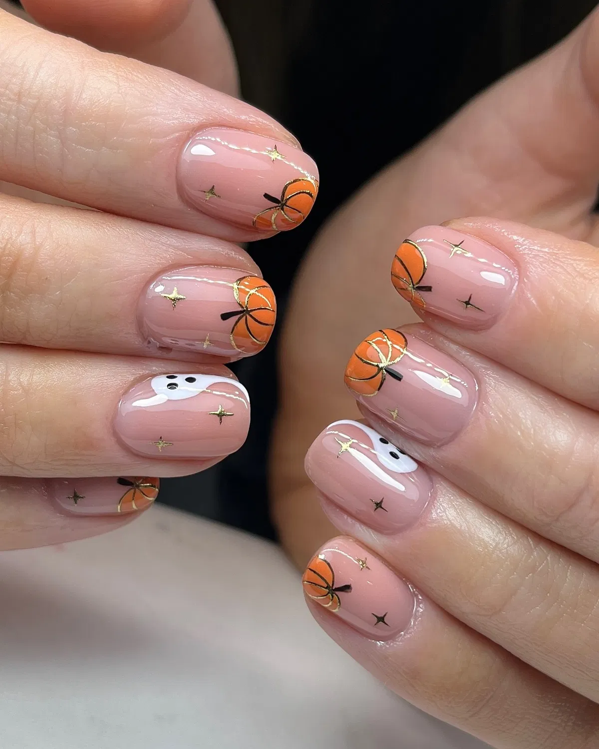 Sheer pink nails with gold stars, pumpkins, and a small ghost accent