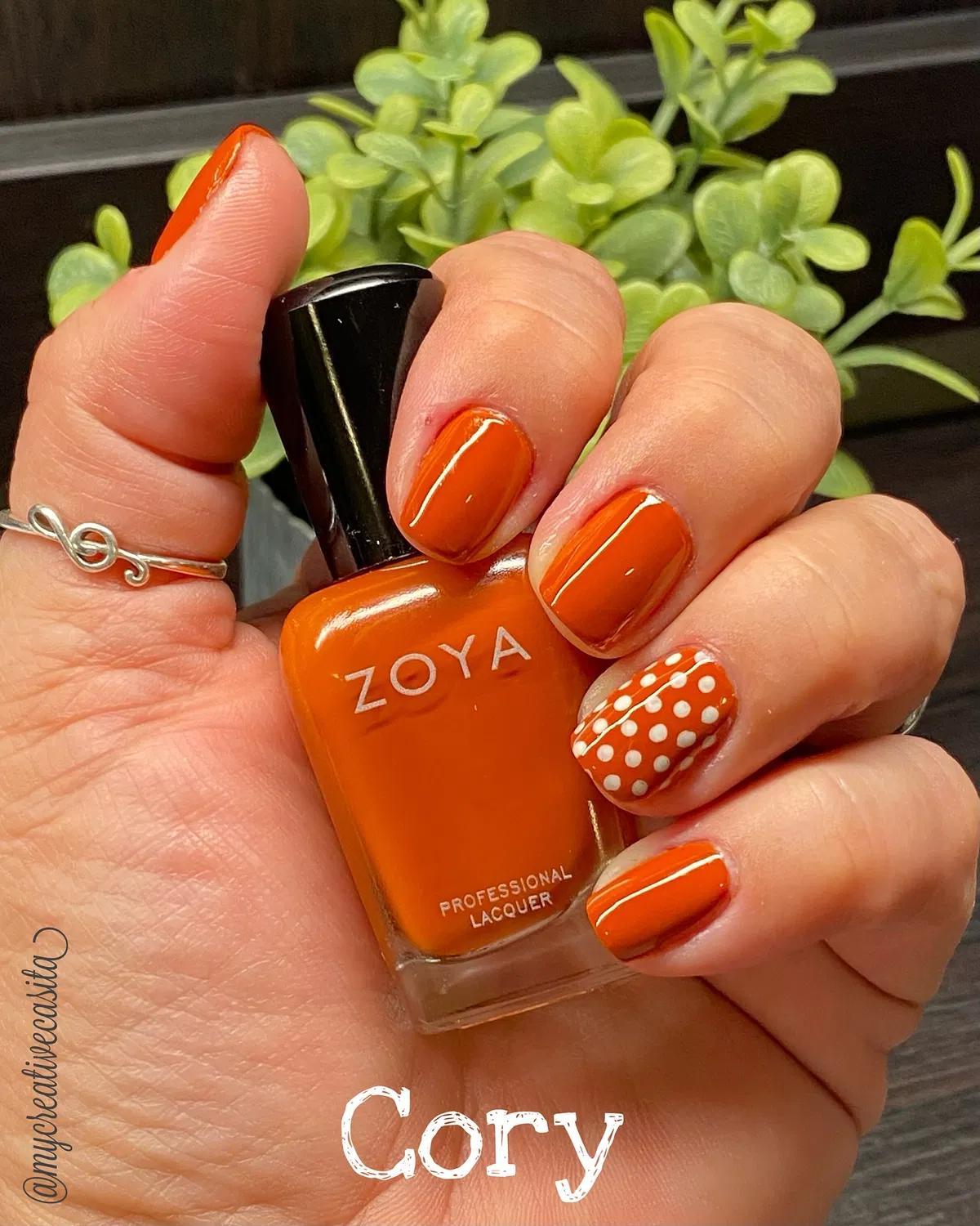 Bright orange manicure with white polka-dot accent