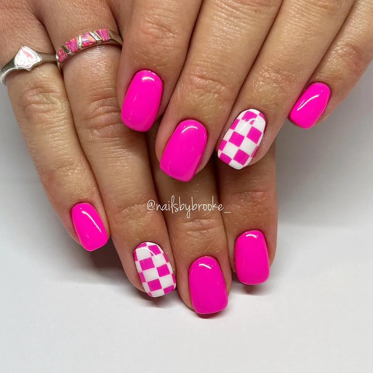 Hot pink glossy nails with checkerboard accents