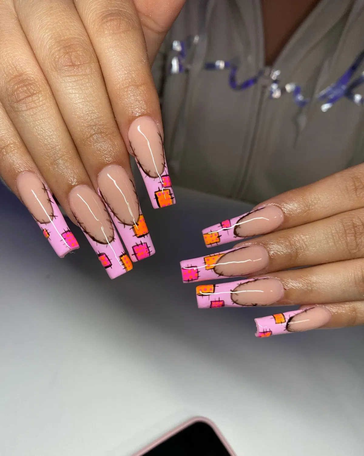 Nude-to-pink tips with orange square motifs and black outlines